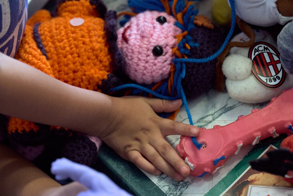 Mano di un bambino tra giocattoli usati su uno scaffale